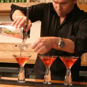 bartender filling three urban bar classic martini glasses